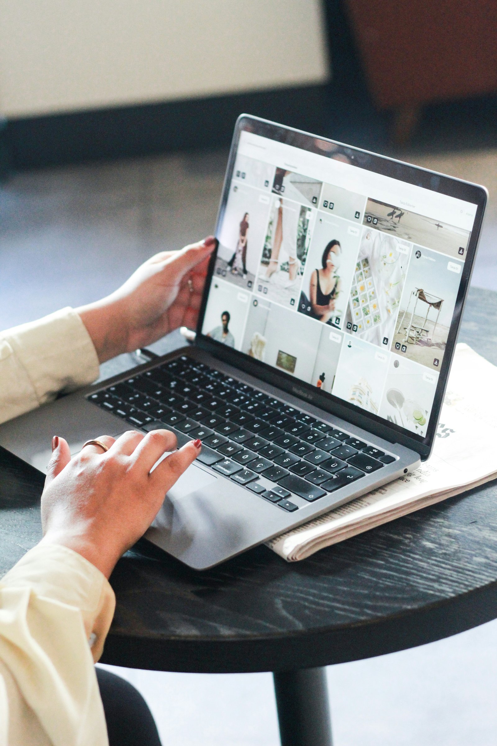 Laptop screen showing photo upload interface with grid of wedding photos, bright airy studio workspace
